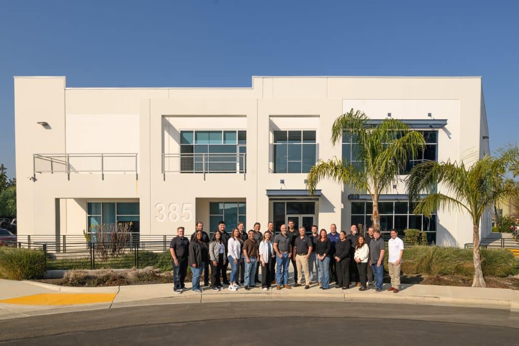 A group of people stand in front of a modern white office building numbered 385.