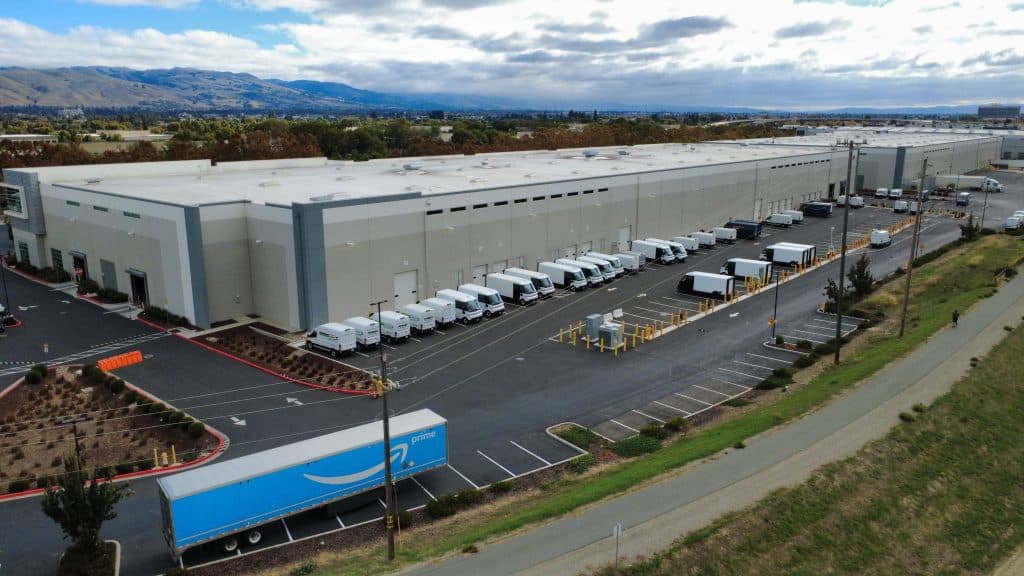Aerial view of a large warehouse with several delivery trucks parked outside.