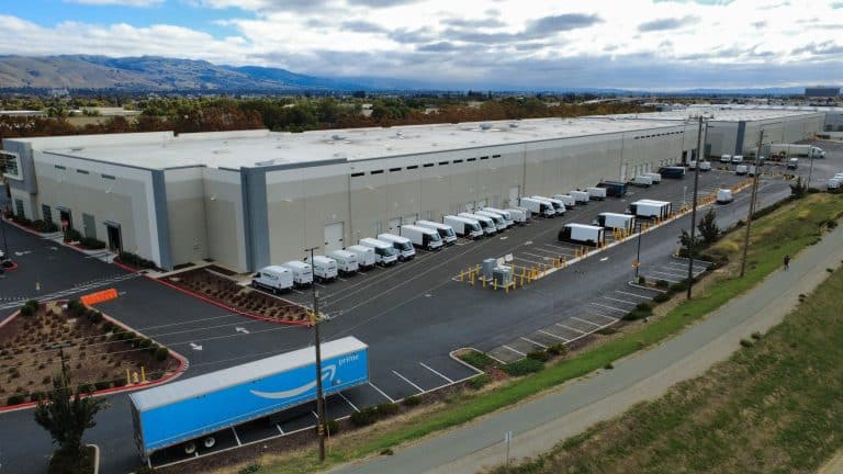 Aerial view of a large warehouse with several delivery trucks parked outside.