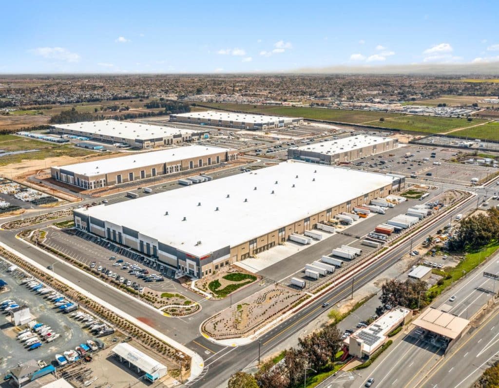 Aerial view of large warehouse buildings with trucks parked in an industrial complex.