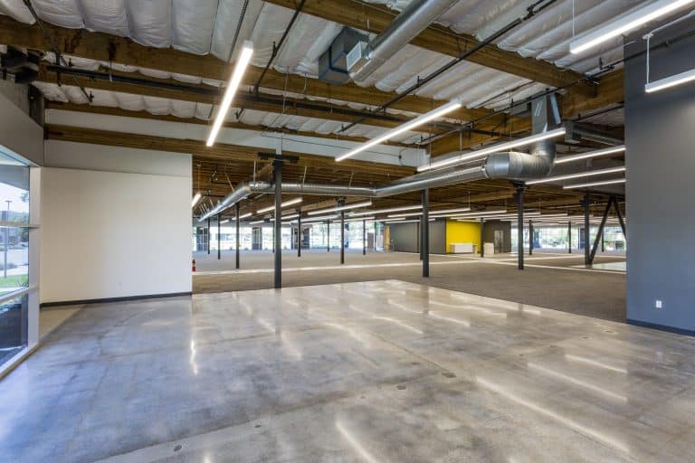 Spacious, modern, empty office space with exposed ceiling and polished concrete floors.