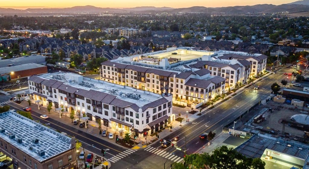 Aerial view of a modern apartment complex and surrounding streets at sunset.