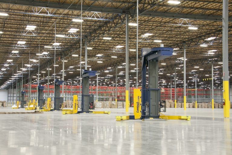 Large, well-lit warehouse interior with automated machinery and stacked goods in the background.