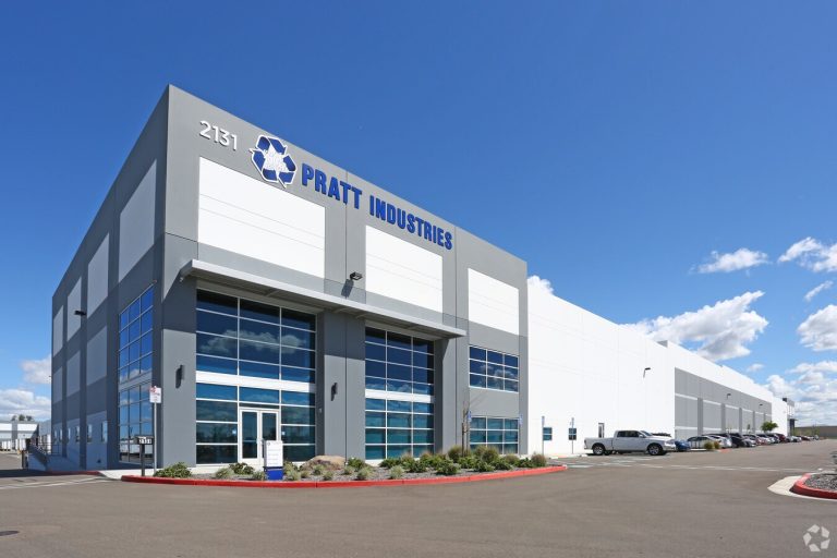 Large modern warehouse building with Pratt Industries sign and parked cars outside.