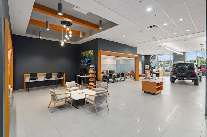 Modern car dealership lobby with seating, desks, and a Jeep SUV on display.