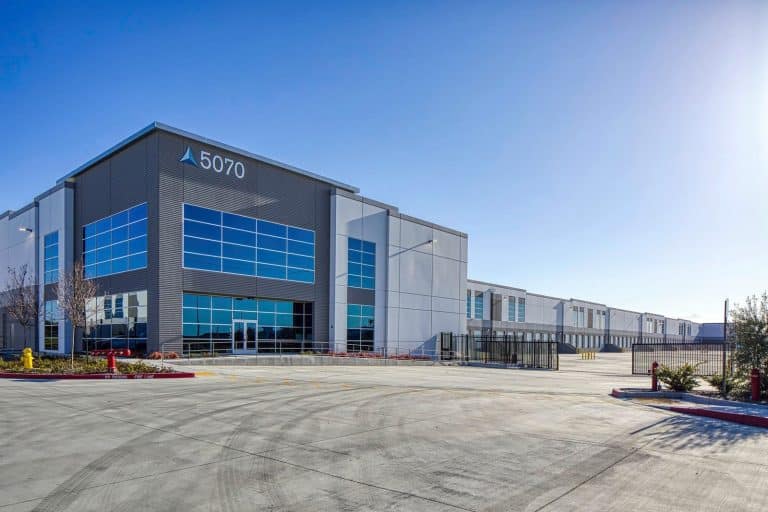 Large modern warehouse building with blue windows and the number 5070 on the exterior.